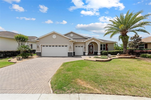 view of front of property featuring a garage, stucco siding, a front lawn, and decorative driveway