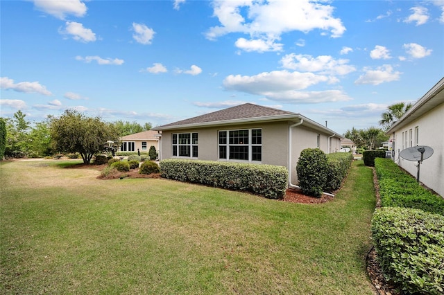 rear view of house featuring a lawn and stucco siding