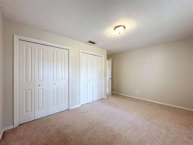 5327 SW 89th St, Ocala, FL 34476 - unfurnished bedroom featuring two closets, a textured ceiling, baseboards, and light colored carpet