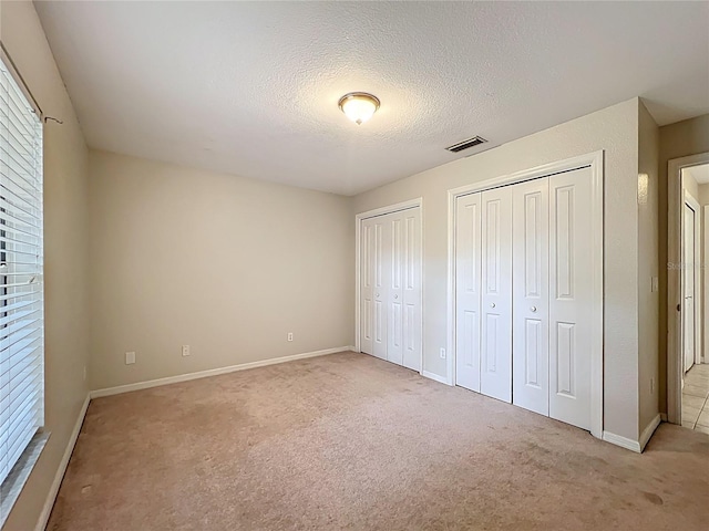 5327 SW 89th St, Ocala, FL 34476 - unfurnished bedroom with two closets, a textured ceiling, visible vents, and light carpet