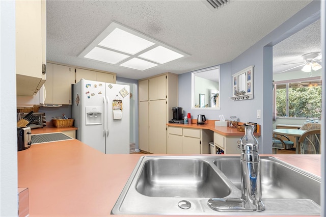 10989 SW 86th Ave, Ocala, FL 34481 - kitchen with a textured ceiling, a sink, white refrigerator with ice dispenser, visible vents, and cream cabinetry
