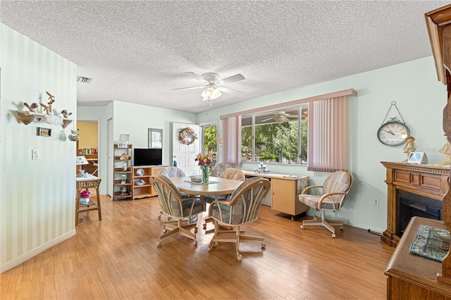 10989 SW 86th Ave, Ocala, FL 34481 - dining space with a fireplace with raised hearth, ceiling fan, visible vents, light wood-style flooring, and a textured ceiling