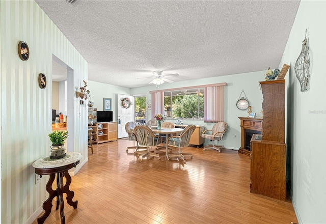 10989 SW 86th Ave, Ocala, FL 34481 - dining area with light wood-type flooring, a ceiling fan, a textured ceiling, and a fireplace