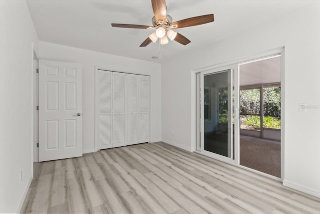 unfurnished bedroom with wood finished floors, a closet, baseboards, and access to exterior