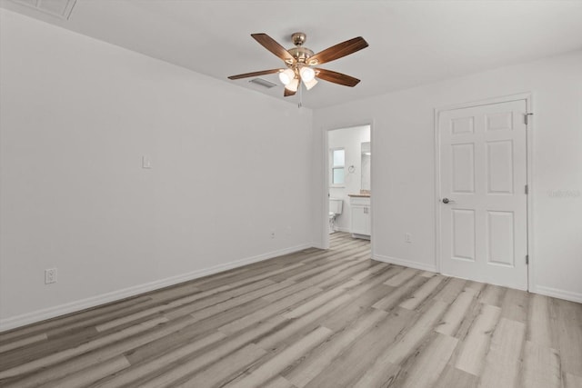 interior space with light wood-type flooring, ensuite bath, baseboards, and visible vents
