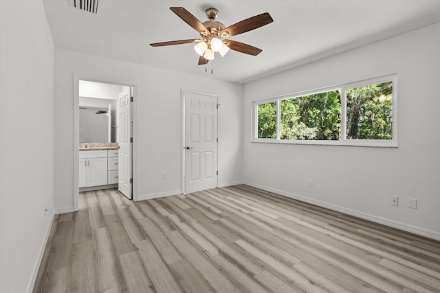 unfurnished bedroom featuring connected bathroom, baseboards, light wood finished floors, and visible vents