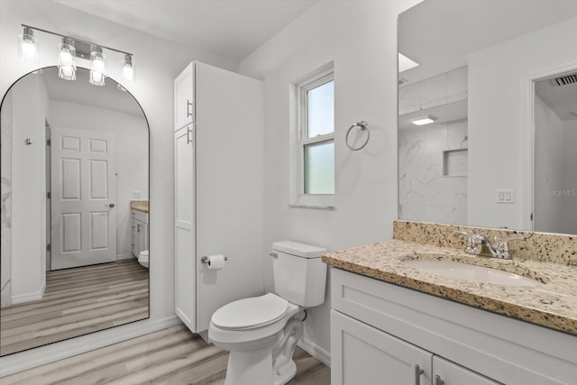 full bath featuring toilet, baseboards, walk in shower, wood finished floors, and vanity