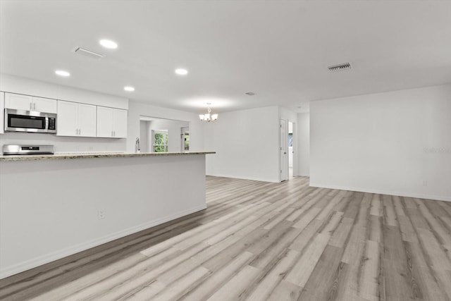 kitchen with stainless steel appliances, visible vents, light wood-style floors, a chandelier, and white cabinetry
