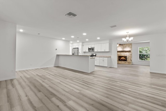 unfurnished living room with an inviting chandelier, light wood-style flooring, visible vents, and recessed lighting