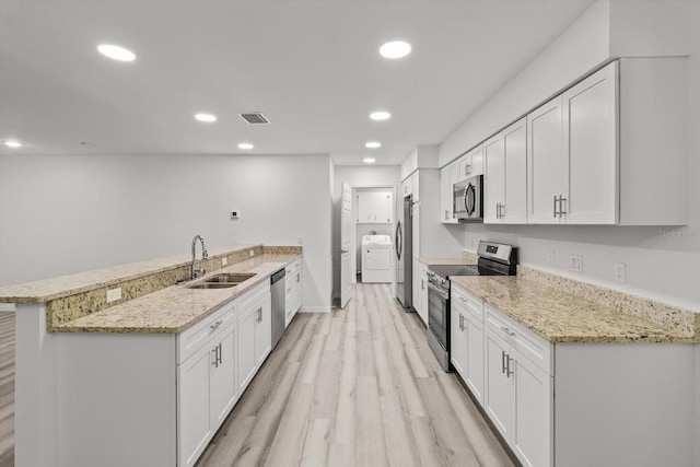kitchen with a sink, light wood-style floors, a peninsula, appliances with stainless steel finishes, and visible vents