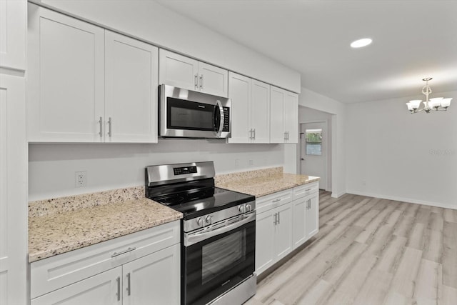kitchen featuring stainless steel appliances, white cabinetry, light wood finished floors, a notable chandelier, and light stone countertops