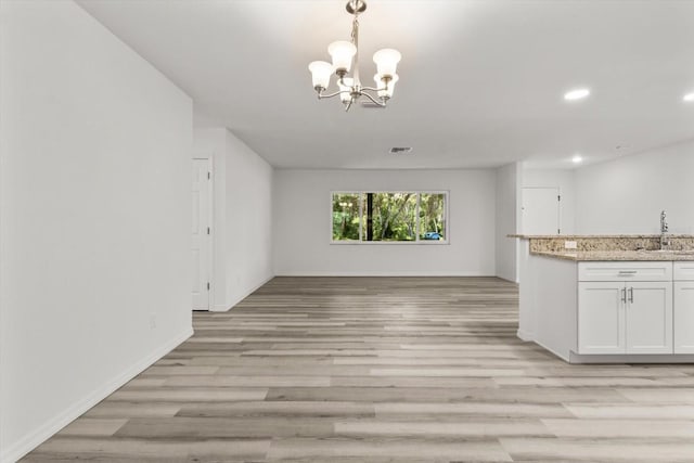 interior space with a chandelier, light wood-type flooring, indoor wet bar, baseboards, and recessed lighting