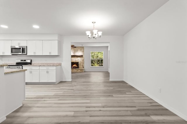 kitchen featuring white cabinets, light wood finished floors, stainless steel appliances, and an inviting chandelier