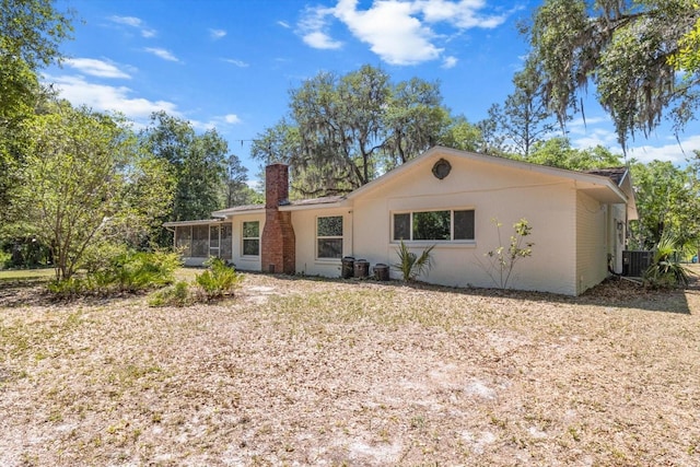 back of house with a sunroom, central AC, and a chimney