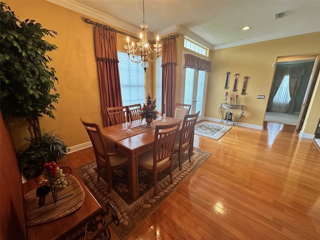 dining room featuring wood finished floors, visible vents, crown molding, baseboards, and a notable chandelier