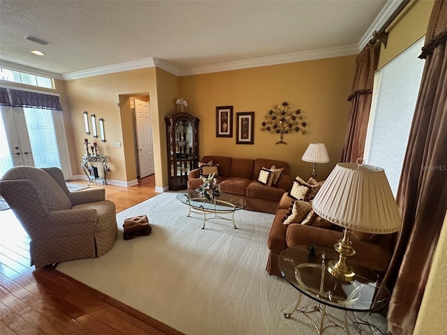 living area with wood finished floors, visible vents, crown molding, and baseboards