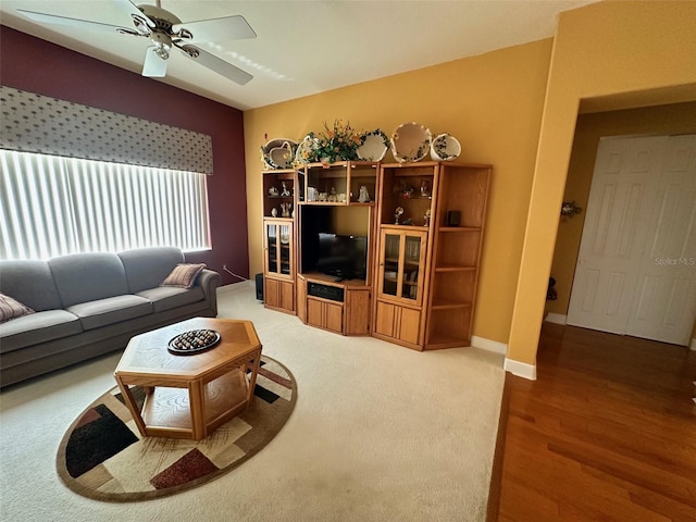 living area with baseboards, wood finished floors, and ceiling fan