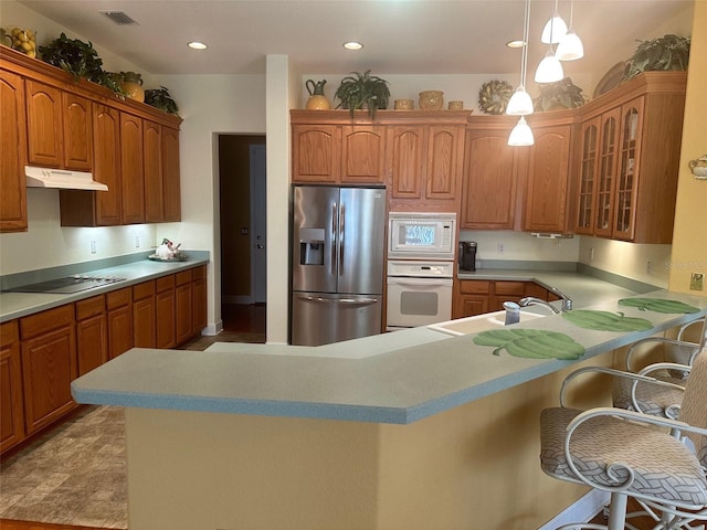 kitchen featuring a sink, visible vents, glass insert cabinets, white appliances, and under cabinet range hood