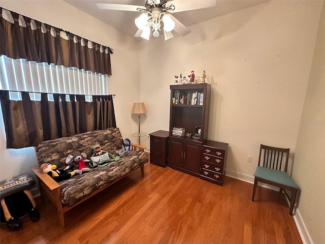 sitting room with ceiling fan, baseboards, and wood finished floors