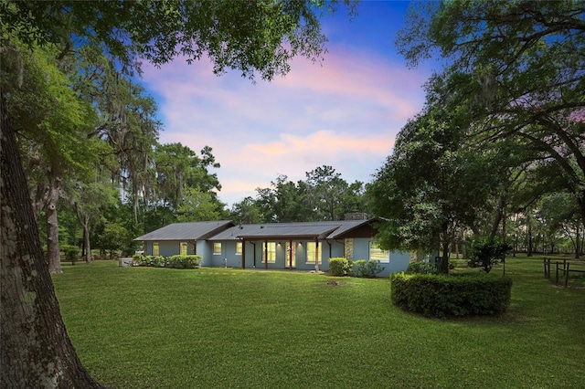 back of property at dusk with a yard and metal roof