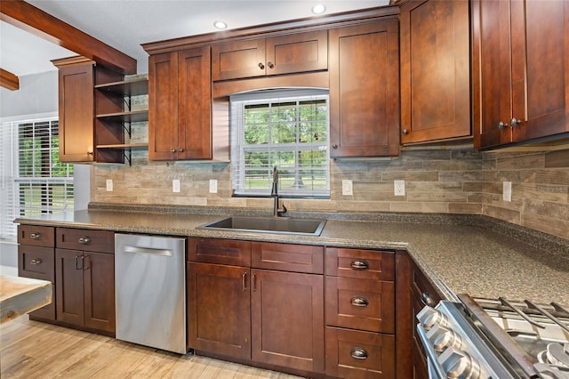 kitchen with light wood-style flooring, a sink, open shelves, dark countertops, and appliances with stainless steel finishes