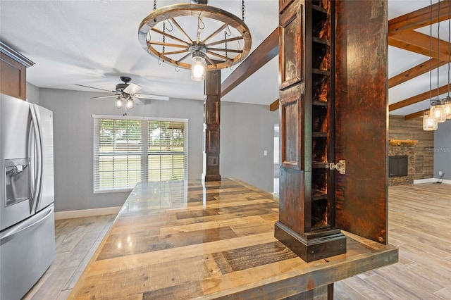kitchen with stainless steel fridge, a fireplace, ceiling fan with notable chandelier, baseboards, and wood finished floors