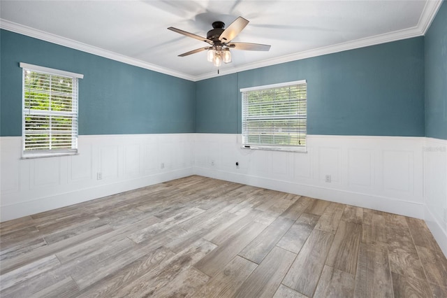 spare room with wood finished floors, ceiling fan, a wainscoted wall, and a wealth of natural light