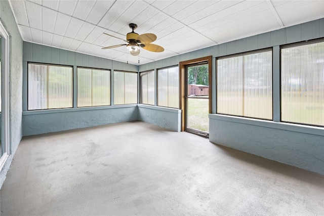 unfurnished sunroom featuring a ceiling fan and concrete floors