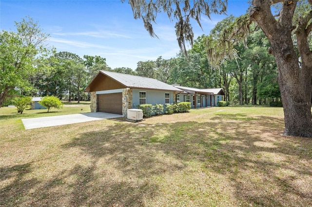 view of home's exterior with driveway, a yard, stone siding, and metal roof