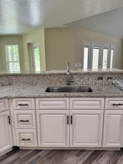 kitchen featuring white cabinets, a sink, and light stone counters
