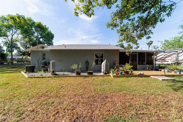 back of property with fence, a lawn, a sunroom, and central AC