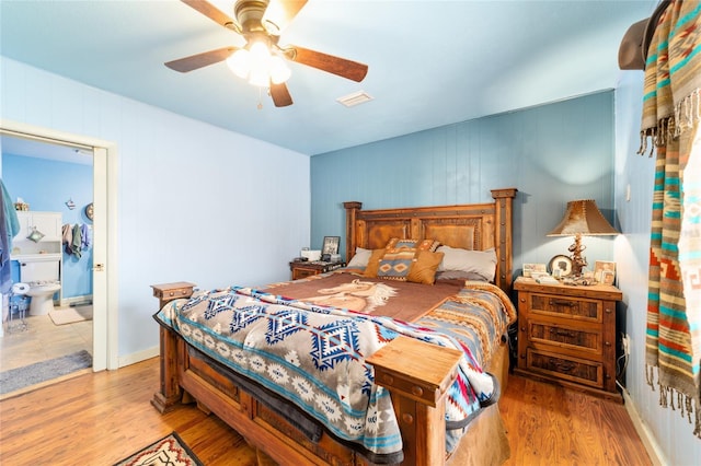bedroom with ensuite bath, wood finished floors, visible vents, and a ceiling fan