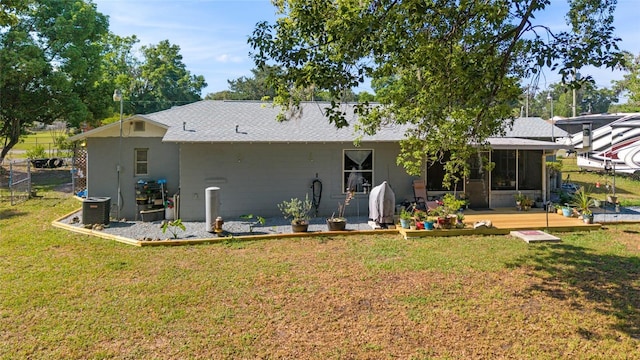 rear view of property with a lawn, central air condition unit, fence, a wooden deck, and a sunroom