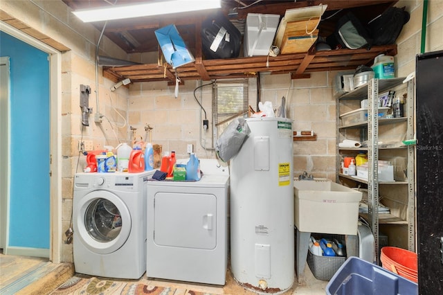 clothes washing area featuring washing machine and clothes dryer, water heater, a sink, and laundry area