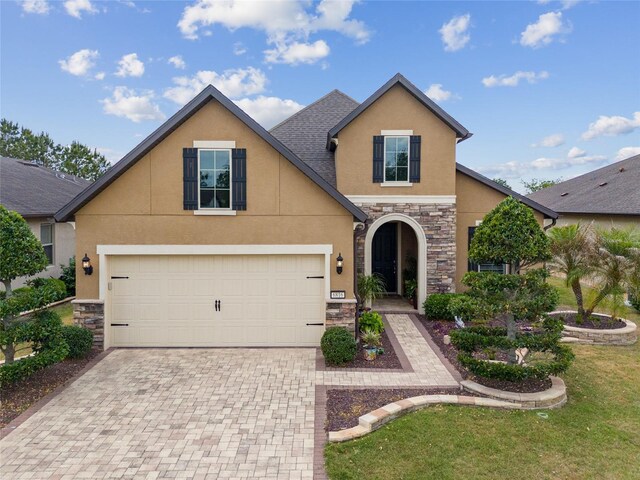 6816 SW 95th Cir, Ocala, FL 34481 - view of front facade featuring stone siding, decorative driveway, a front yard, stucco siding, and a garage
