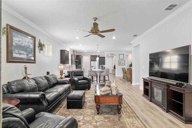 6816 SW 95th Cir, Ocala, FL 34481 - living room featuring visible vents, ornamental molding, a ceiling fan, and light wood finished floors