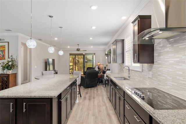 6816 SW 95th Cir, Ocala, FL 34481 - kitchen with black electric cooktop, a sink, light wood-style floors, a ceiling fan, and wall chimney range hood