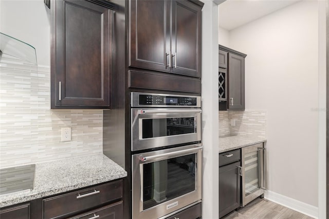 6816 SW 95th Cir, Ocala, FL 34481 - kitchen featuring dark brown cabinets, stainless steel double oven, light wood-style floors, backsplash, and wine cooler
