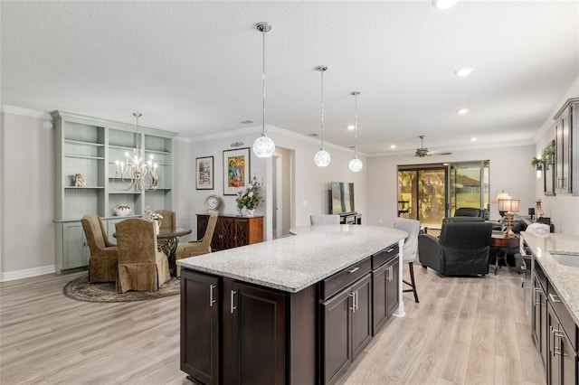 6816 SW 95th Cir, Ocala, FL 34481 - kitchen with dark brown cabinets, ceiling fan with notable chandelier, open floor plan, light wood-style floors, and light stone countertops