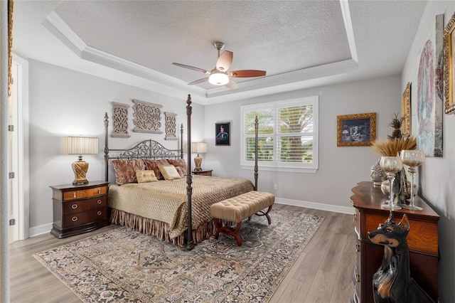 6816 SW 95th Cir, Ocala, FL 34481 - bedroom with wood finished floors, a ceiling fan, a textured ceiling, and a tray ceiling