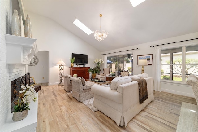 living room featuring high vaulted ceiling, a skylight, an inviting chandelier, light wood-style flooring, and a brick fireplace