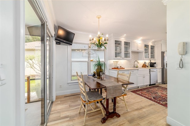 dining space with ornamental molding, baseboards, a notable chandelier, and light wood-style floors
