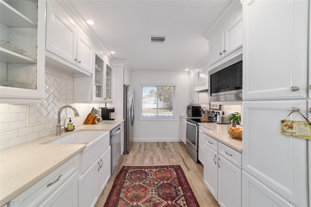 kitchen with light wood finished floors, white cabinets, a sink, visible vents, and appliances with stainless steel finishes