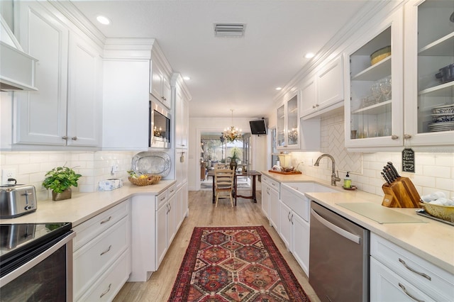 kitchen with a sink, a chandelier, stainless steel appliances, white cabinets, and visible vents