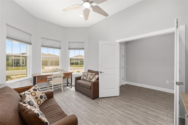 living area with light wood-type flooring, baseboards, ceiling fan, and a healthy amount of sunlight