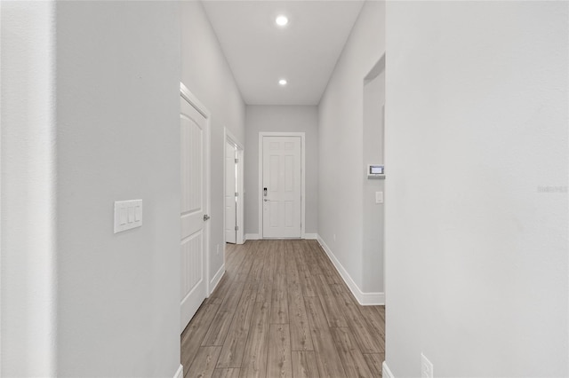 hallway with recessed lighting, light wood finished floors, and baseboards