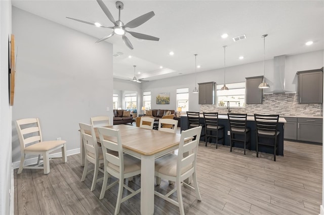 dining space featuring light wood-style flooring, visible vents, a ceiling fan, and a healthy amount of sunlight