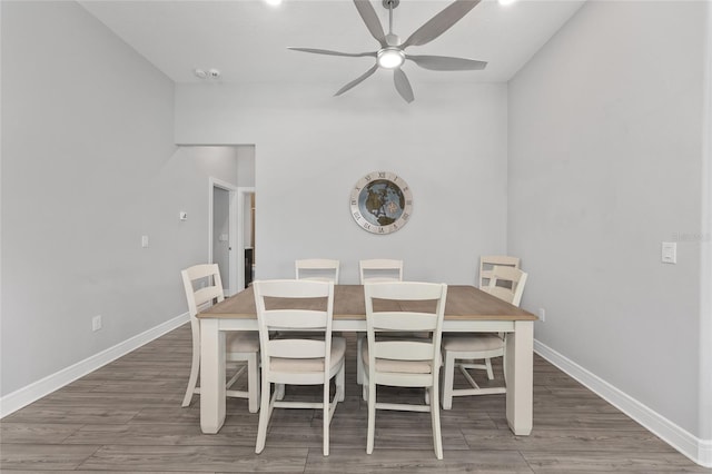 dining room with wood finished floors, a ceiling fan, and baseboards
