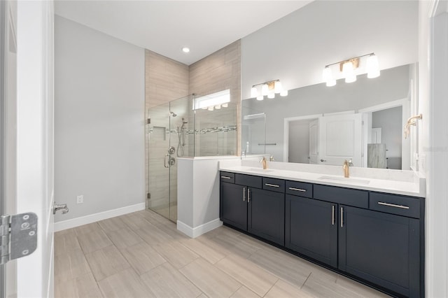 bathroom with double vanity, a shower stall, baseboards, and a sink