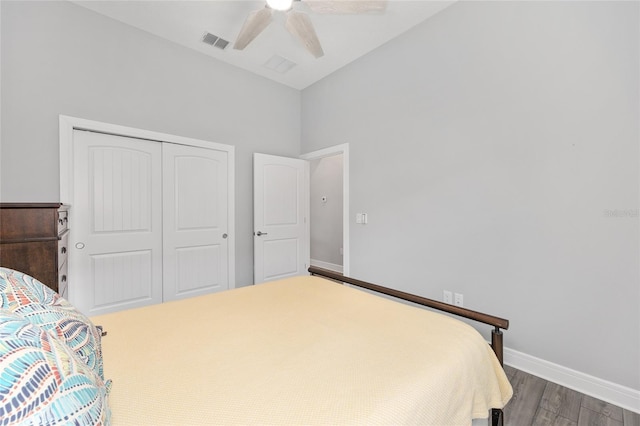 bedroom featuring vaulted ceiling, a closet, dark wood finished floors, baseboards, and visible vents